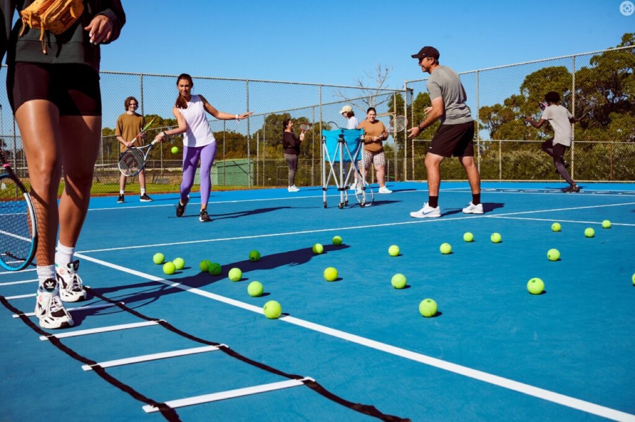 Adults in a coaching and cardio tennis session on court
